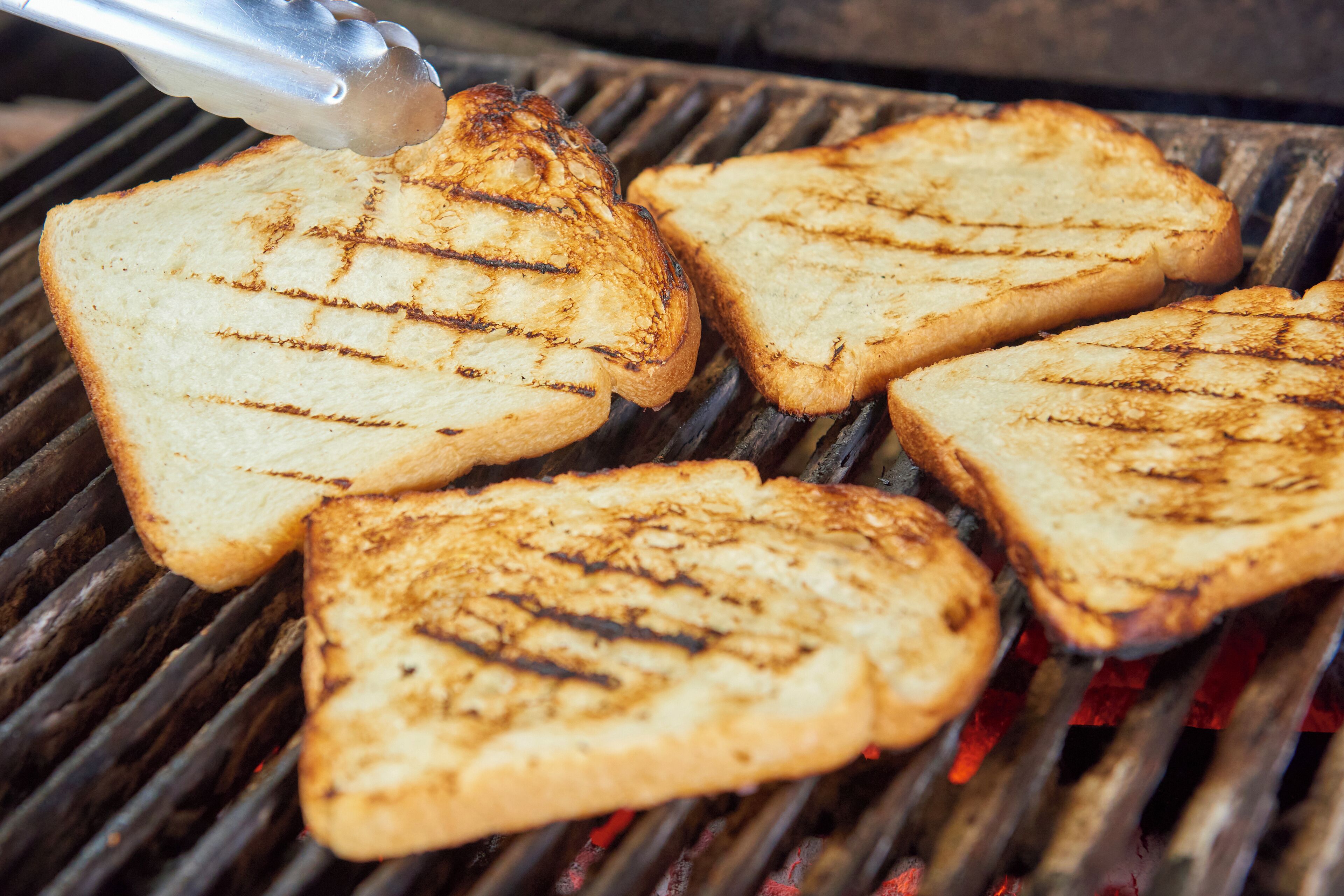 Four slices of grilled toast on a grill.
