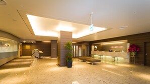 Un moderno vestíbulo de hotel con mostrador de recepción, zona de estar y una planta grande.