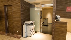 Zona de recepción de hotel con puerta a sala privada, mostrador de recepción e impresora.