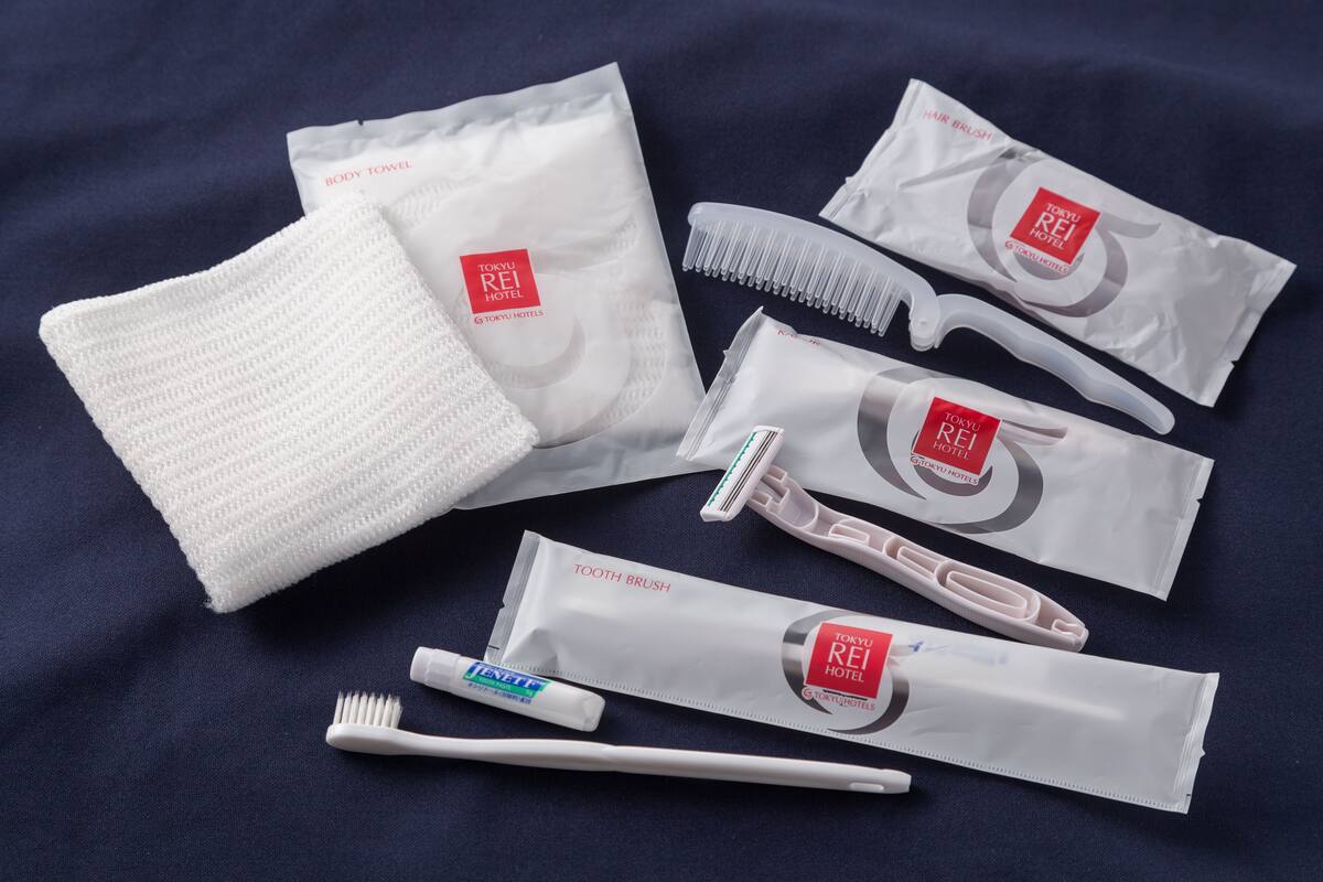 Diverse toiletartikelen, waaronder een handdoek, haarborstel, kam, tandenborstel en tandpasta, allemaal met het logo van Tokyo Rei Hotel.