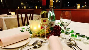 Una mesa para dos, con una botella de vino, copas y una vela.