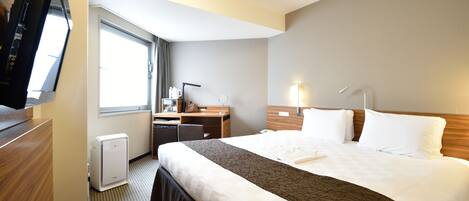 Habitación de hotel con una cama grande, un escritorio, una silla, un televisor y una ventana.