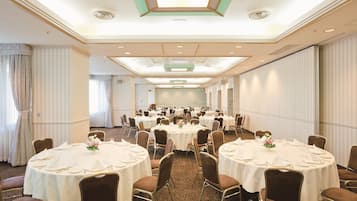 A banquet hall with round tables set for dining, equipped with chairs and table settings.