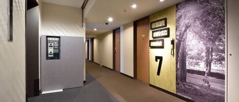 A hotel hallway with a card reader, numbered doors, and a large wall mural.
