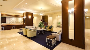 A spacious lobby with a reception desk, seating area, and a staircase. - Kobe Sannomiya Tokyu REI Hotel (Kobe)