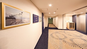 A hallway with framed artwork, a patterned carpet, and a view into another room. - Kobe Sannomiya Tokyu REI Hotel (Kobe)