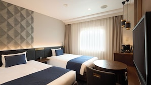 A hotel room with two beds, a desk, a chair, a TV, and a large window with curtains. - Kobe Sannomiya Tokyu REI Hotel (Kobe)