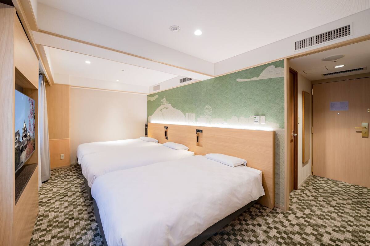 A hotel room with two beds, a green mural, and a checkered floor.