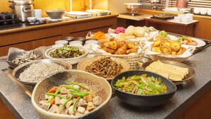 Un bufé con diversos platos, incluyendo fideos, verduras y pastelería.