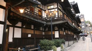 Un edificio japonés tradicional con arquitectura de madera, varios balcones y faroles colgantes.