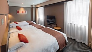 Habitación de hotel con dos camas, televisión y ventana con cortinas.
