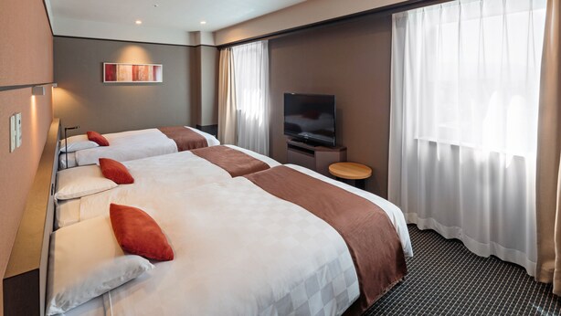 Een hotelkamer met twee bedden, een televisie en een raam met gordijnen.