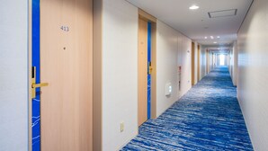 A hotel corridor with wooden doors numbered 413, a blue carpet, and a long hallway with white walls and ceiling lights. - Matsuyama Tokyu REI Hotel (Matsuyama)