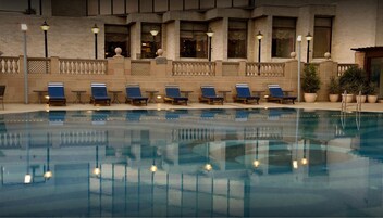 An indoor swimming pool with lounge chairs and a stone wall with windows.