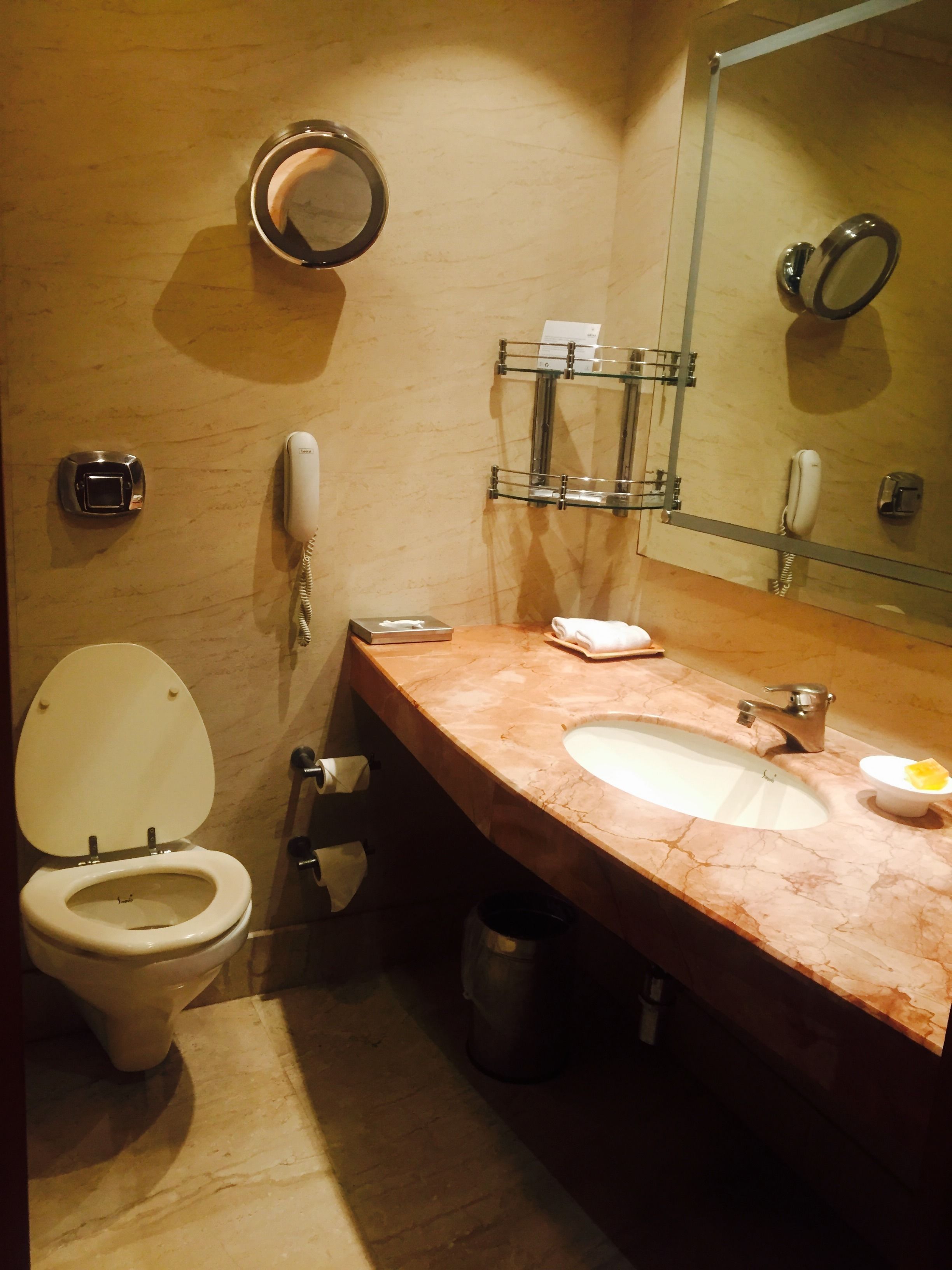 A bathroom with a toilet, sink, mirror, and two phones.