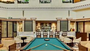 Un tavolo da biliardo in un'area relax della hall dell'hotel, con un bar e posti a sedere.