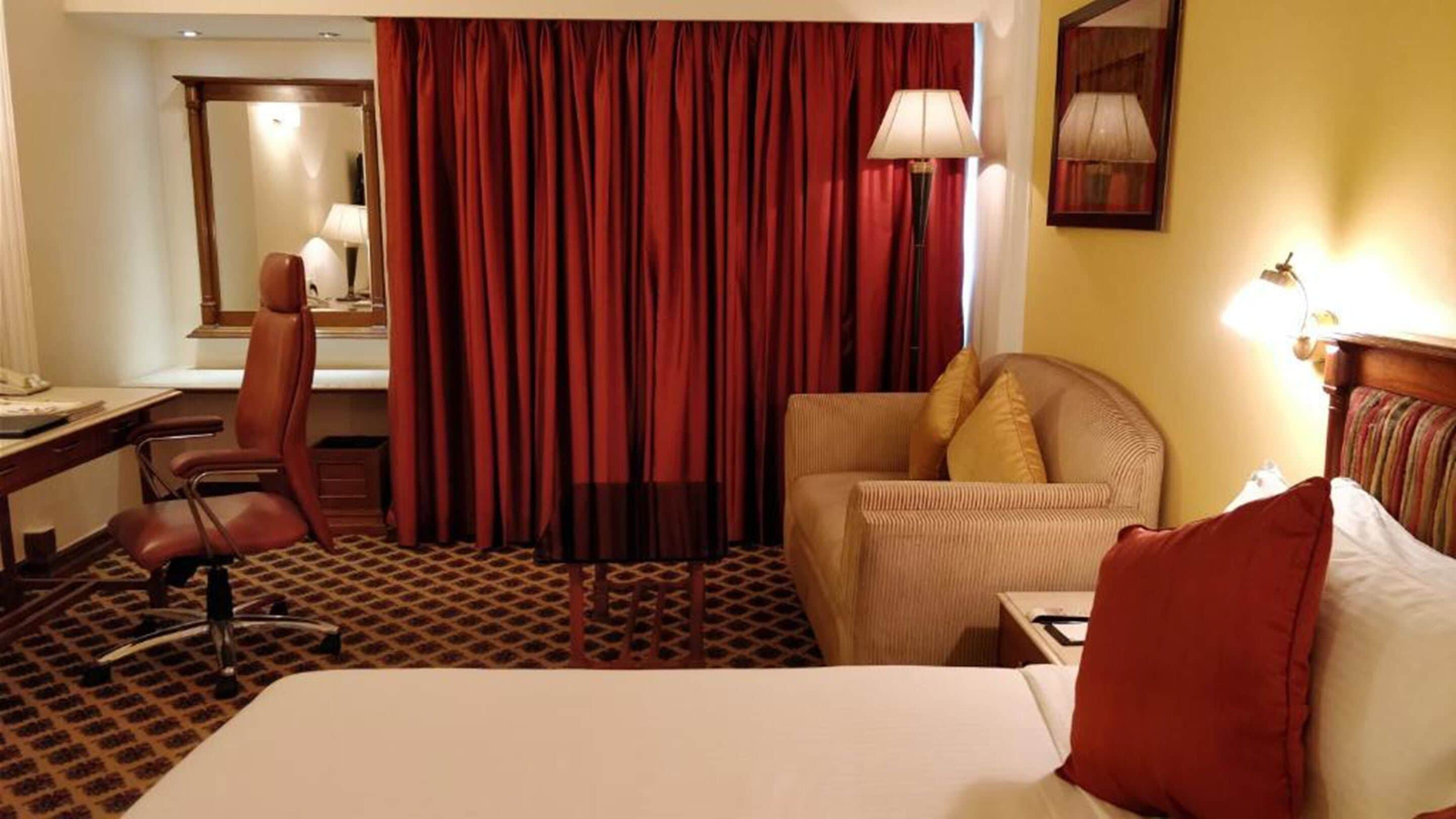 A hotel room with a bed, a desk, a chair, and a sofa.