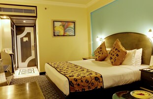 A hotel room with a large bed, a desk, and a chair.