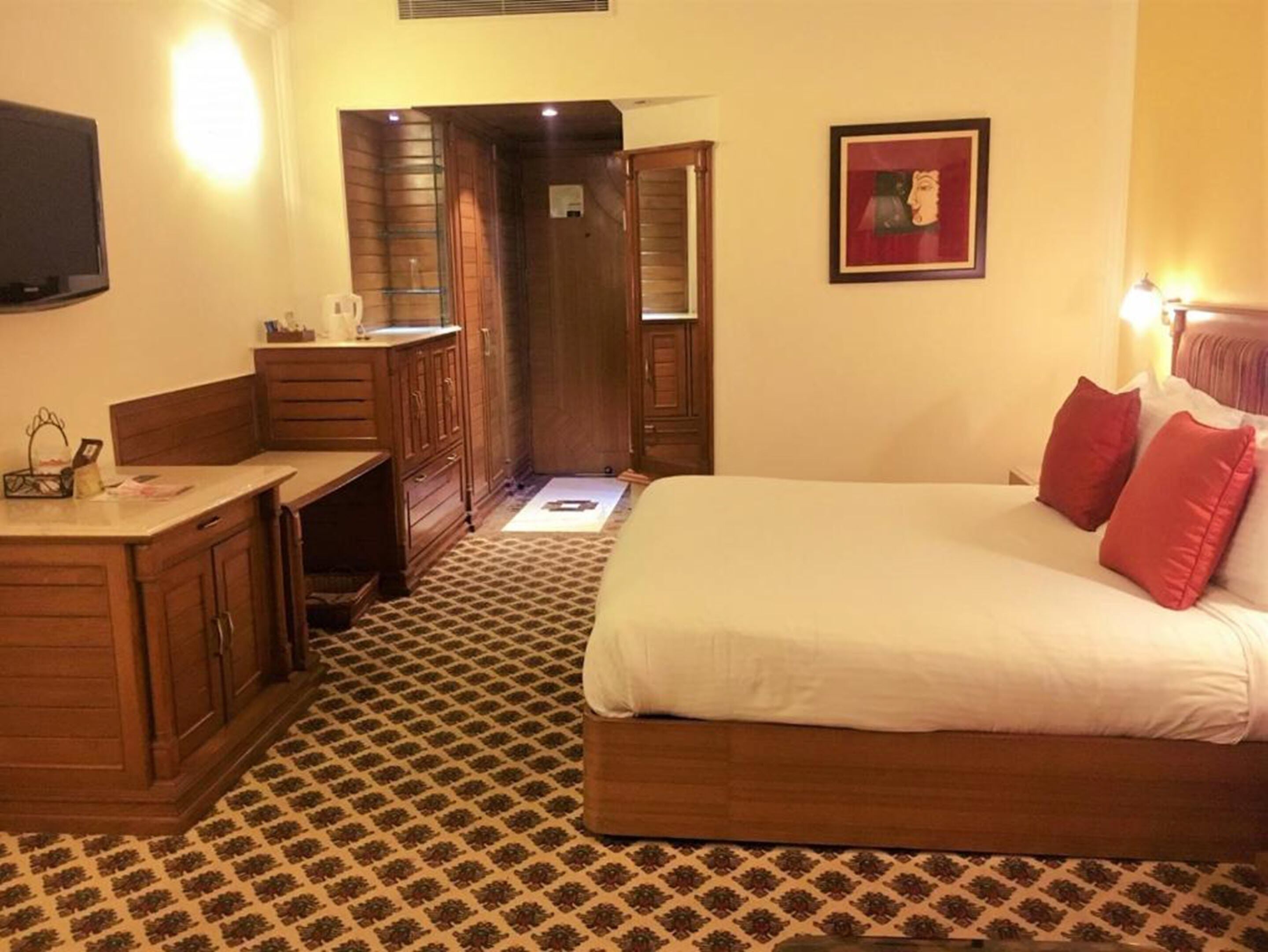 Quarto de hotel com uma cama, uma escrivaninha e um guarda-roupa.