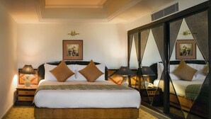 Una camera d'albergo con un letto grande, un comodino con una lampada, un armadio con uno specchio e un quadro appeso al muro.