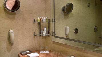 Un baño con lavamanos de mármol, un espejo grande, un perchero y un estante con artículos de aseo.
