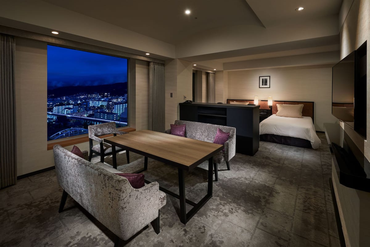 Een moderne hotelkamer met stadszicht, een zithoek, een bed en een televisie.