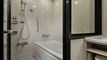 A modern bathroom with a bathtub, shower, and a vanity with a mirror.