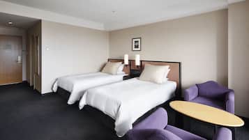 Una habitación de hotel con dos camas, una mesita pequeña y sillas moradas.