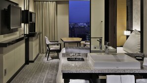 Une salle de bain d’hôtel moderne, dotée d’un grand lavabo, d’un miroir et offrant une vue sur la ville.