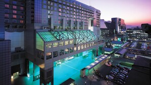 Un hôtel moderne à plusieurs étages, doté d’une façade en verre et d’un parking pouvant accueillir plusieurs voitures.