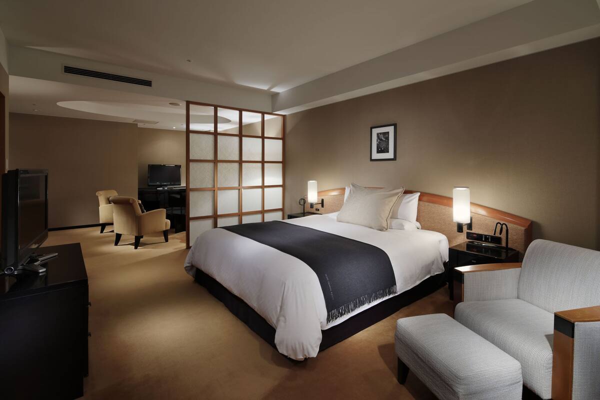 A hotel room with a large bed, a TV, a desk, and a chair.