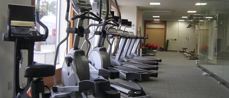 A gym with multiple treadmills, stationary bikes, and an elliptical machine.