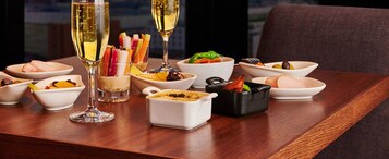 A dining table with various dishes and two glasses of champagne.
