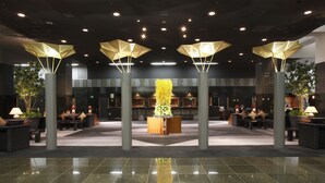 Un hall d’entrée spacieux avec un comptoir d’accueil central, des espaces de détente et des luminaires modernes.