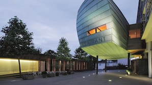A modern building with a curved glass facade and the word "RESTAURANT" on it. - Vienna House by Wyndham Martinspark Dornbirn (Dornbirn)