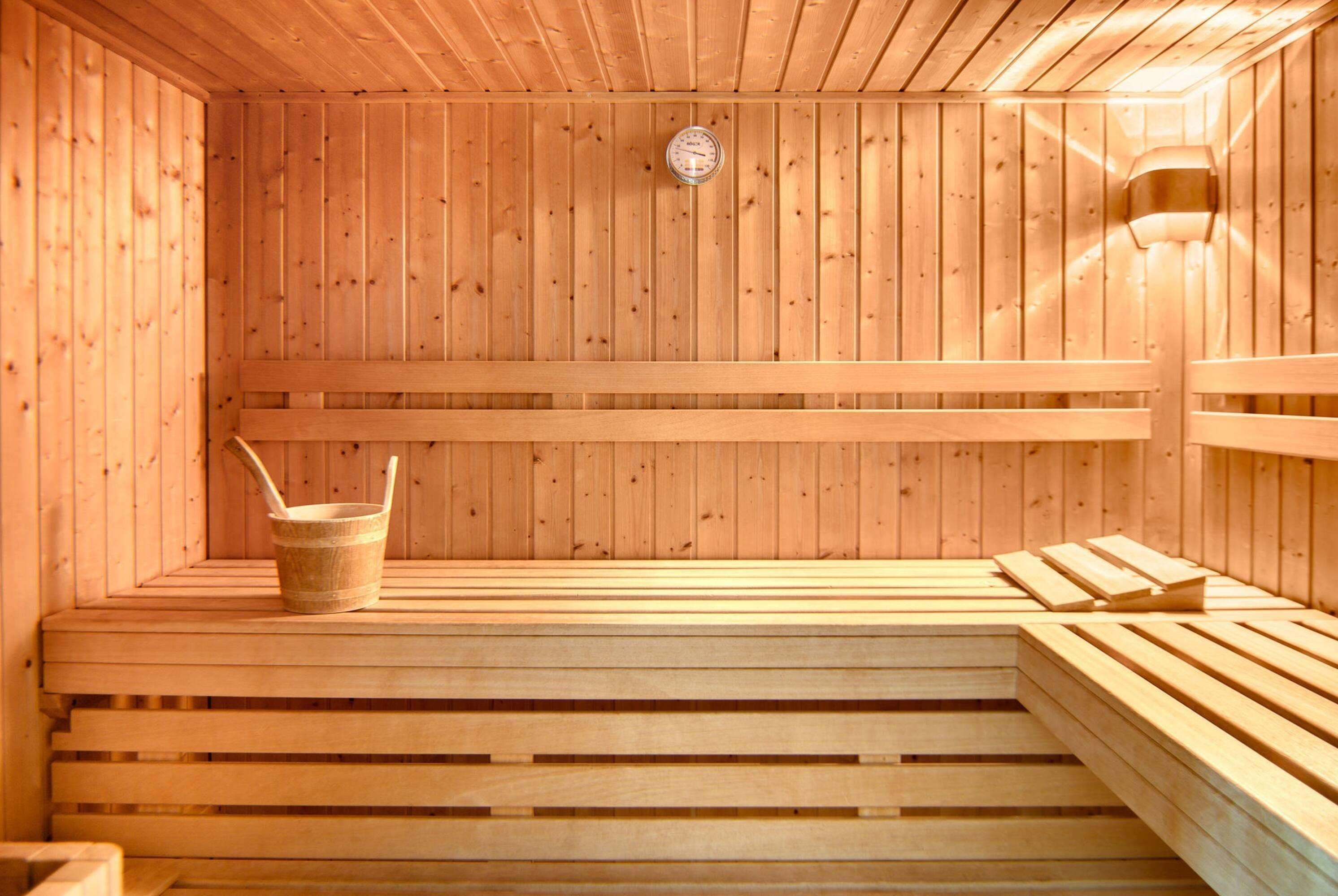 A wooden sauna with benches and a bucket.