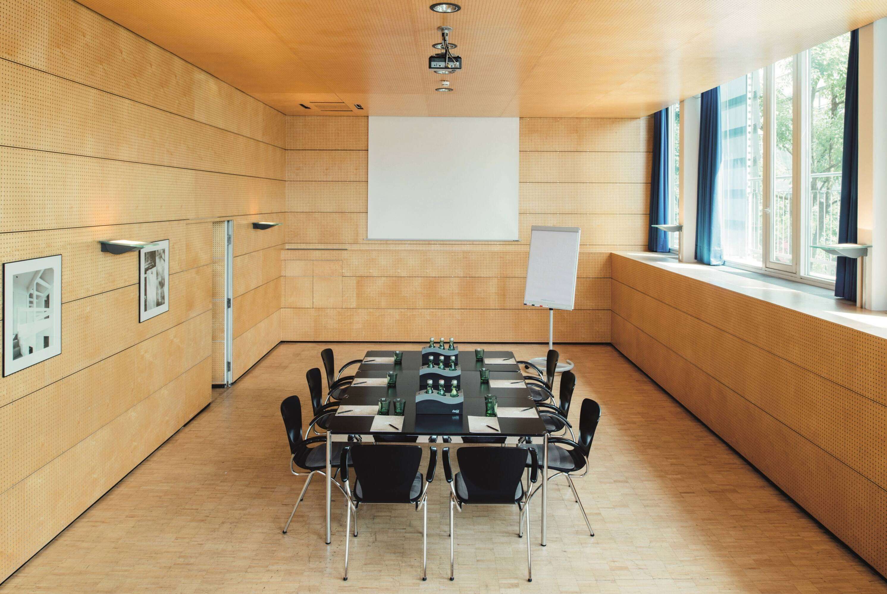 A conference room with a large table, chairs, a projector, and a whiteboard.