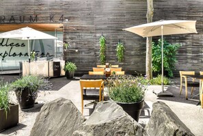 An outdoor seating area with tables and chairs, potted plants, and umbrellas. - Vienna House by Wyndham Martinspark Dornbirn (Dornbirn)