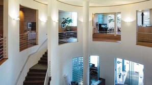 A multi-level interior with a staircase, a dining area, and a view of the outside. - Vienna House by Wyndham Martinspark Dornbirn (Dornbirn)