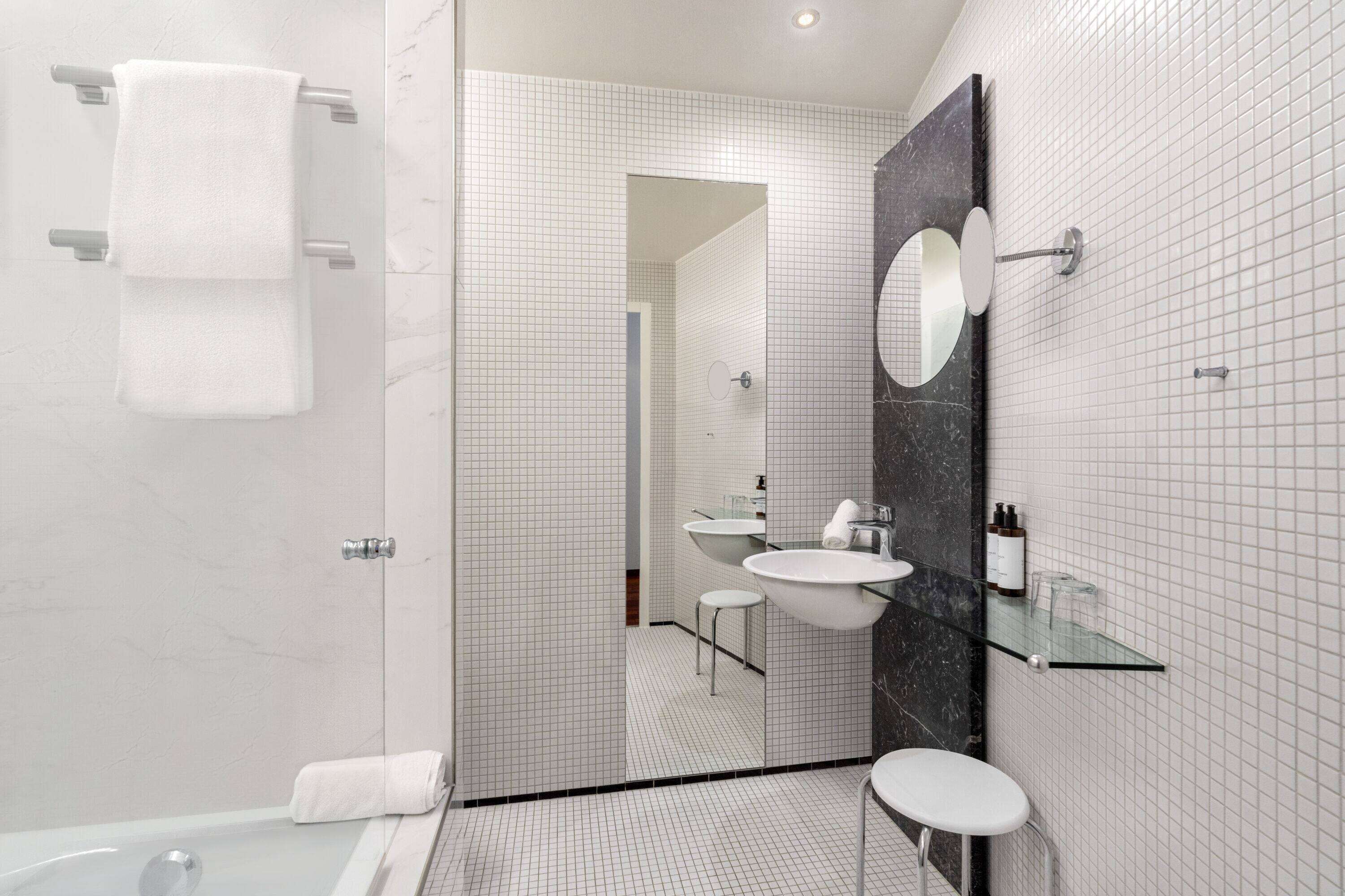 A modern bathroom with a glass shower enclosure, a white sink, and a large mirror.