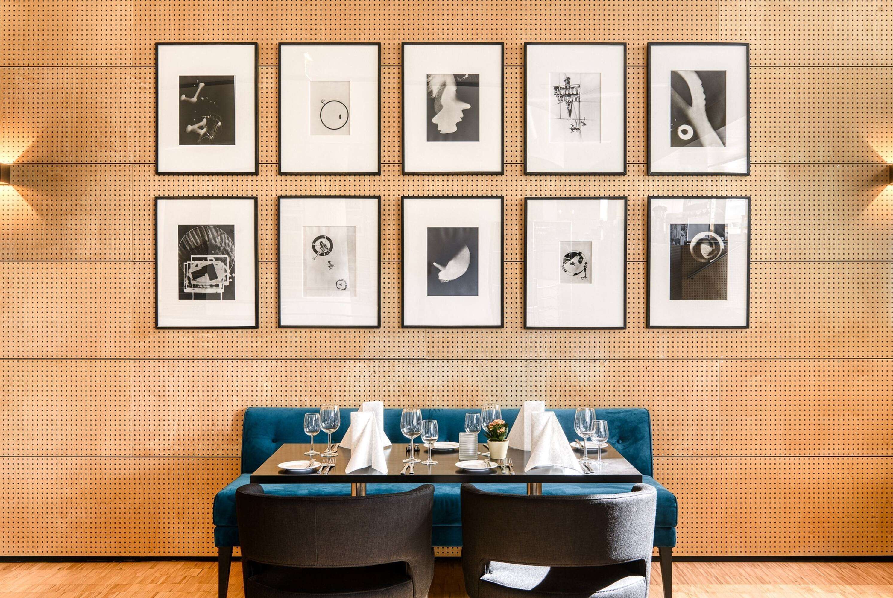 A dining area with a blue booth table set for two, framed artwork on the wall, and a wooden floor.