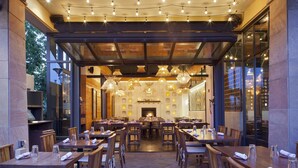 A restaurant with wooden tables and chairs, a stone floor, and hanging light fixtures. - The Westin Westminster (Westminster)