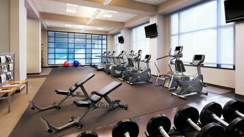 Ett gym med träningsredskap, bänkar för styrketräning och hantlar.