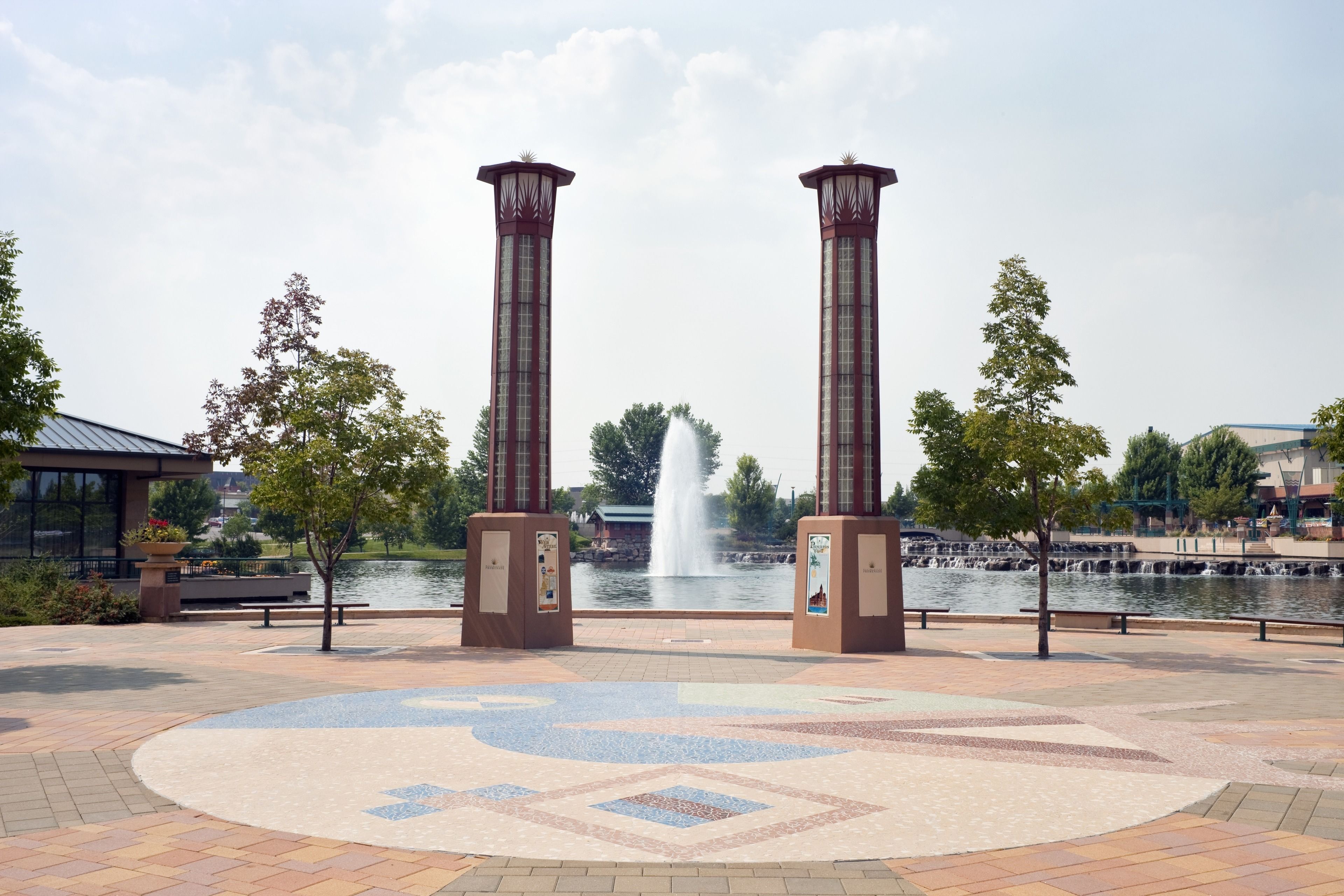 A park with two tall columns, a fountain, and a patterned walkway.
