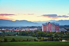 A large hotel with multiple floors and a prominent "Westin" sign, surrounded by green fields and a lake, with mountains in the background. - The Westin Westminster (Westminster)
