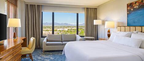 Une chambre d’hôtel avec un grand lit, un canapé, un bureau et une vue sur un paysage montagneux.