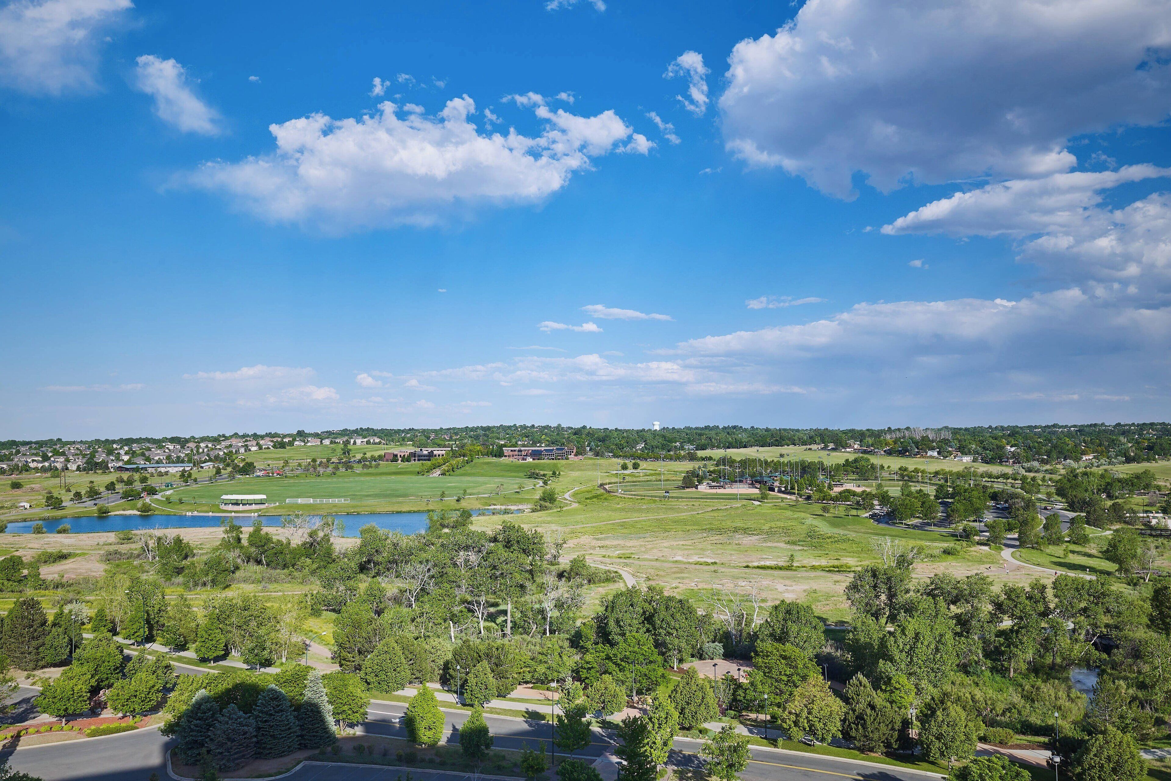 A golf course with a lake, surrounded by trees and residential areas.