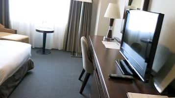 Una habitación de hotel con cama, escritorio, televisión y silla.