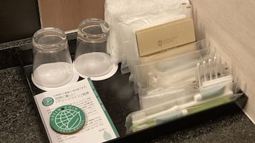 A tray with a green coin, a towel, a box, and a set of toiletries.