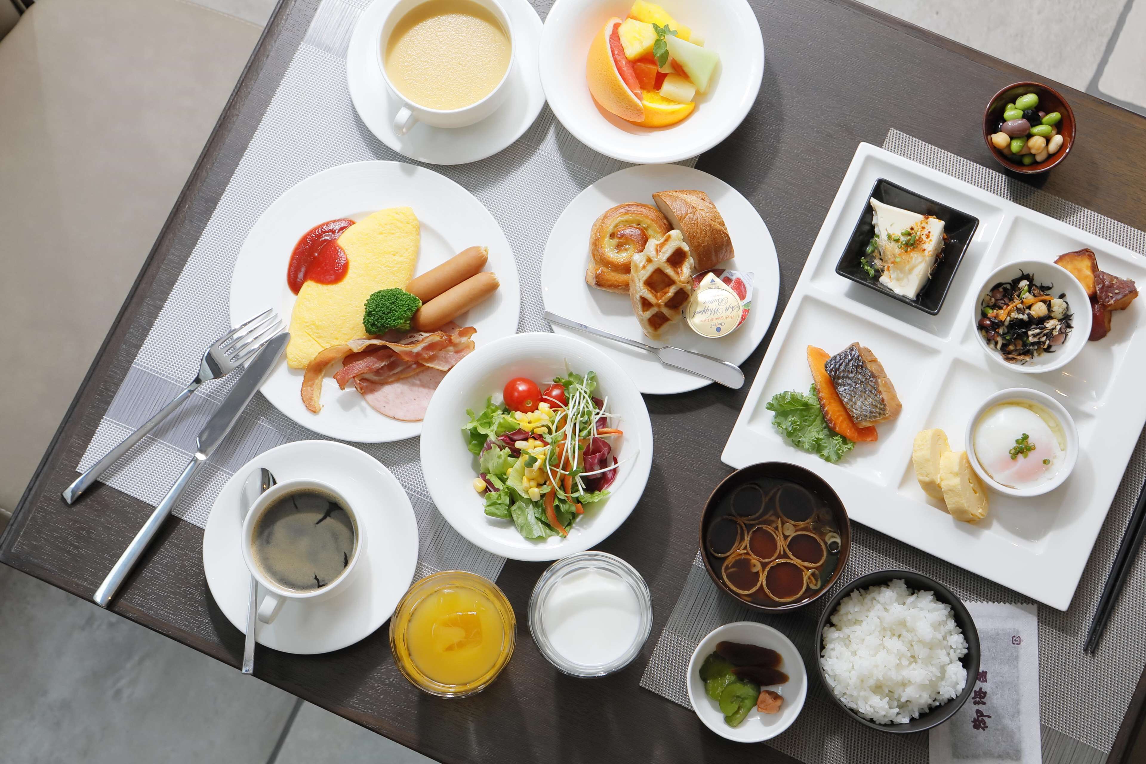 A breakfast table with various dishes including eggs, bacon, toast, and fruit.